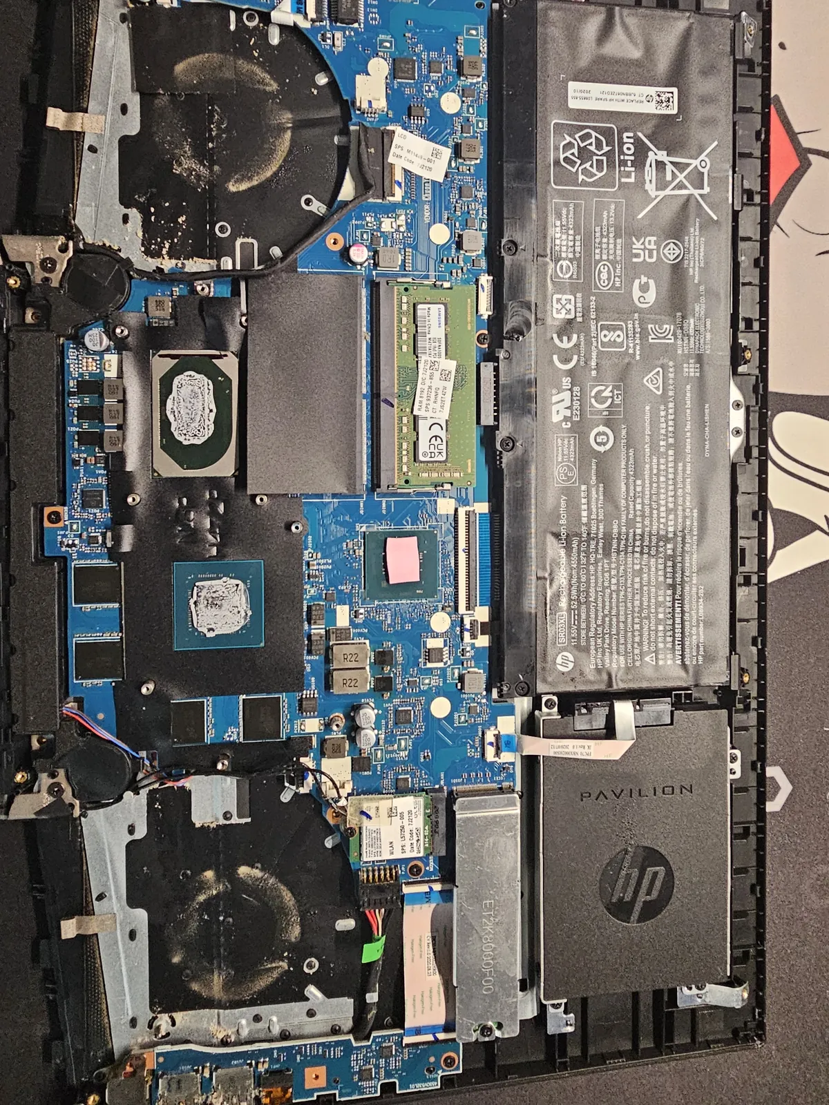PC portable HP ouvert sur l’établi pour un diagnostic : ventilateurs, batterie et carte mère visibles